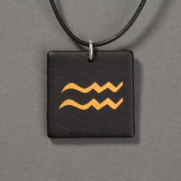 Sandcarved gold and black glass aquarius pendant.