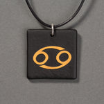 Sandcarved gold and black glass cancer pendant.