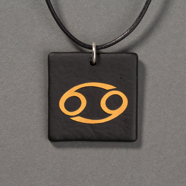 Sandcarved gold and black glass cancer pendant.