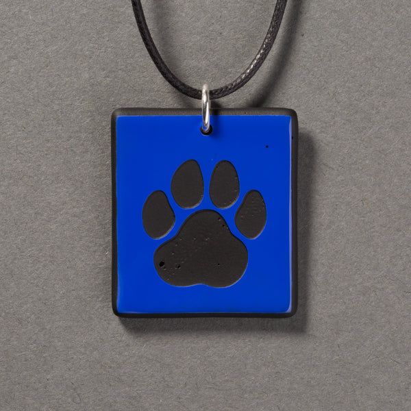 Sandcarved blue and black glass cat paw pendant.