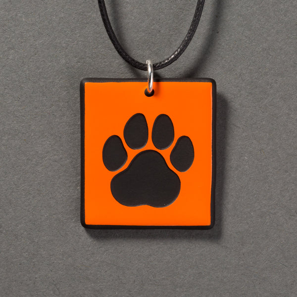 Sandcarved bright orange and black glass cat paw pendant.