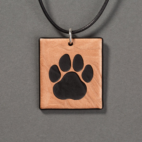 Sandcarved bronze and black glass cat paw pendant.