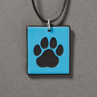 Sandcarved deep sky blue and black glass cat paw pendant.