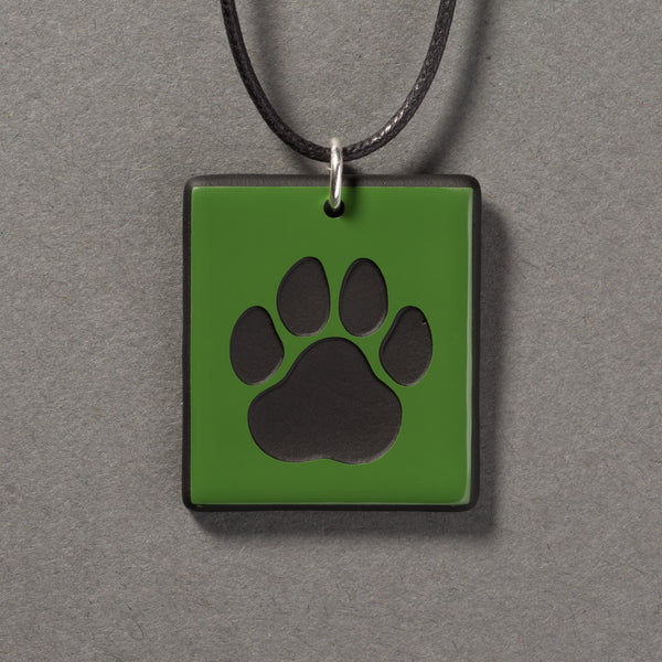 Sandcarved green and black glass cat paw pendant.