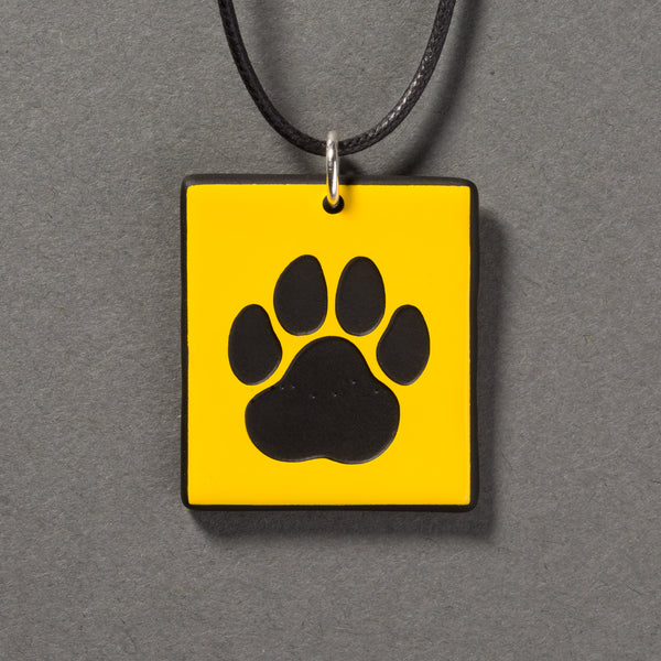 Sandcarved yellow and black glass cat paw pendant.