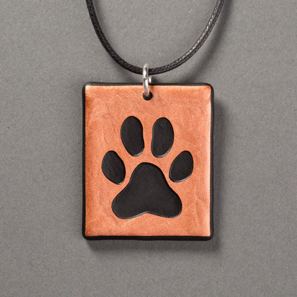 Sandcarved copper and black glass dog paw pendant.