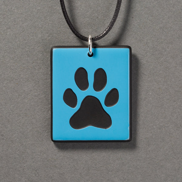 Sandcarved deep sky blue and black glass dog paw pendant.