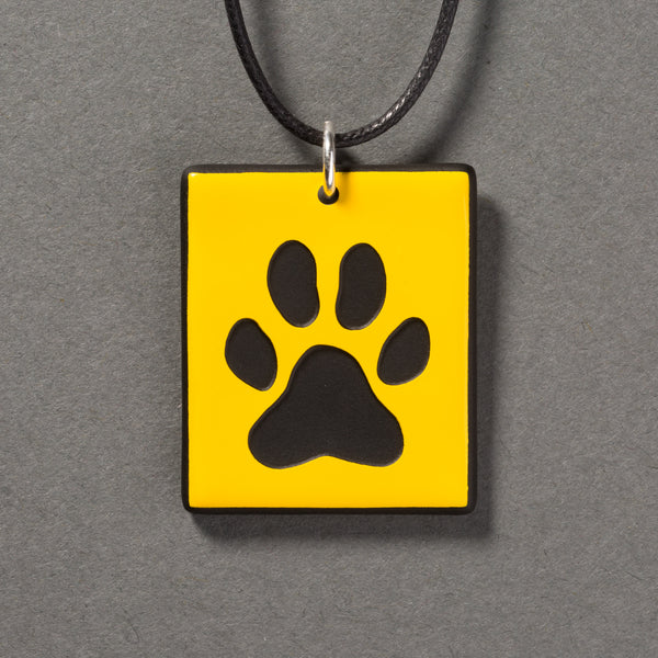 Sandcarved yellow and black glass dog paw pendant.