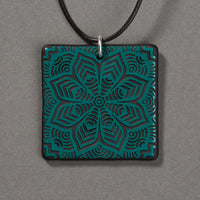 Sandcarved aquamarine and black glass flower mandala pendant.