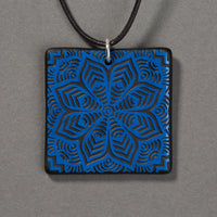 Sandcarved blue and black glass flower mandala pendant.