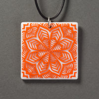 Sandcarved bright orange and white glass flower mandala pendant.