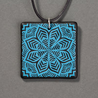 Sandcarved deep sky blue and black glass flower mandala pendant.