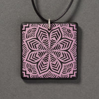 Sandcarved lilac and black glass flower mandala pendant.