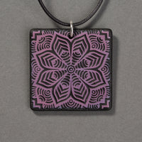 Sandcarved purple and black glass flower mandala pendant.