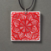 Sandcarved red and white glass flower mandala pendant.