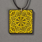 Sandcarved yellow and black glass flower mandala pendant.