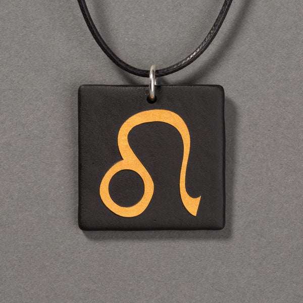 Sandcarved gold and black glass leo pendant.