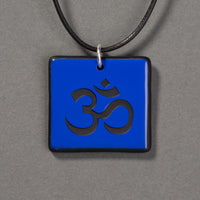 Sandcarved blue and black glass om pendant.