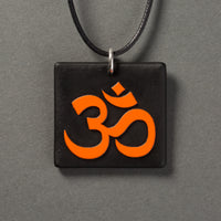 Sandcarved bright orange and black glass om pendant.