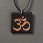 Sandcarved bronze and black glass om pendant.