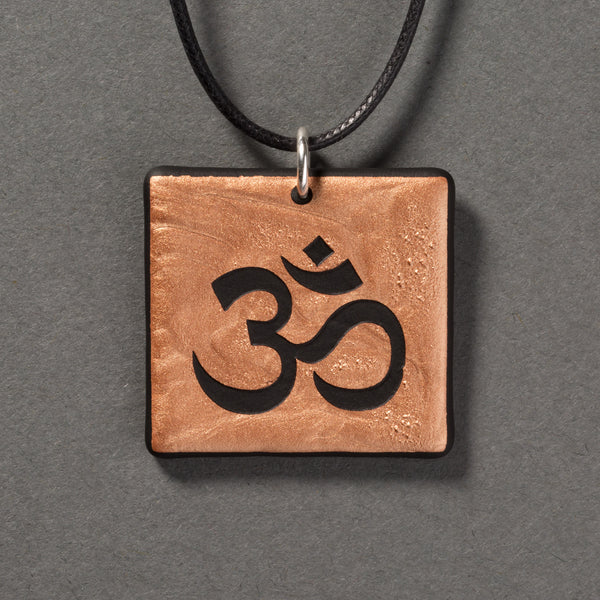 Sandcarved bronze and black glass om pendant.