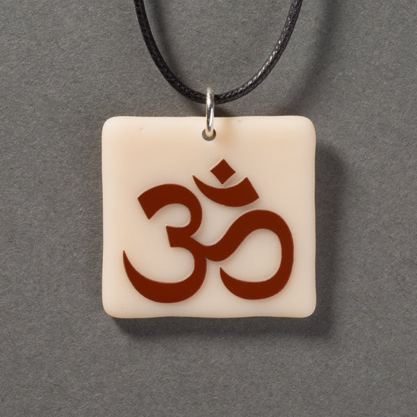 Sandcarved brown and marzipan glass om pendant.