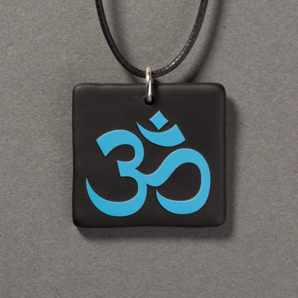 Sandcarved deep sky blue and black glass om pendant.