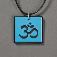 Sandcarved deep sky blue and black glass om pendant.