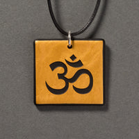 Sandcarved gold and black glass om pendant.