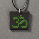 Sandcarved green and black glass om pendant.