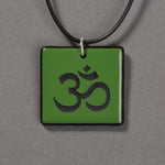 Sandcarved green and black glass om pendant.