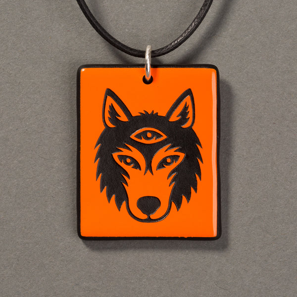 Sandcarved bright orange and black glass silicate wolf logo pendant.