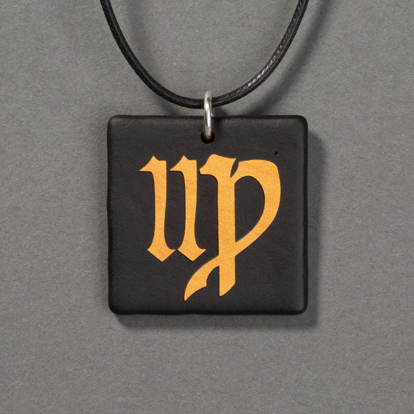 Sandcarved gold and black glass virgo pendant.